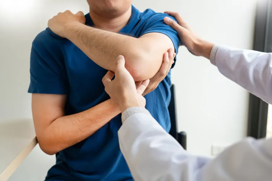 Chiropractor examining a patient’s shoulder and arm